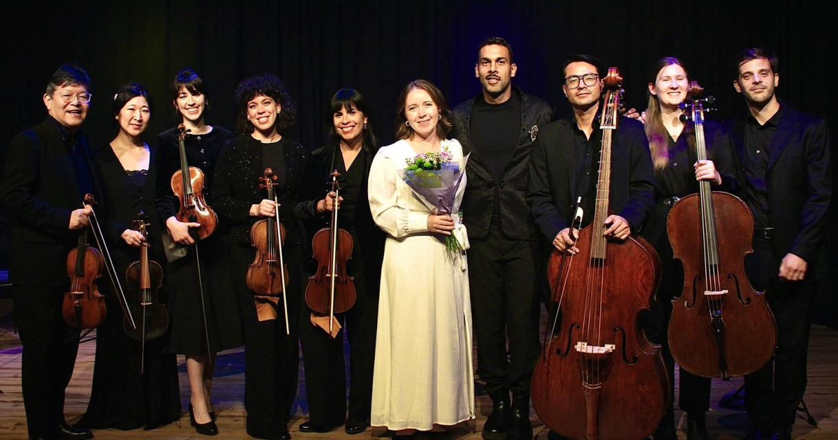 A group of nine musicians posing after a performance.