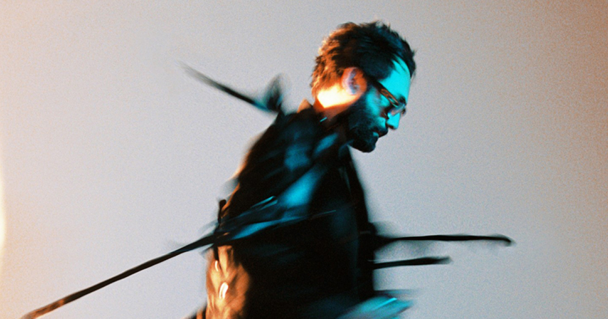 Portret van Blaudzun in blauwe lichtflits, slepend aan touwen – passend bij de herkenbare, intense emotionele lading van zijn muziek.