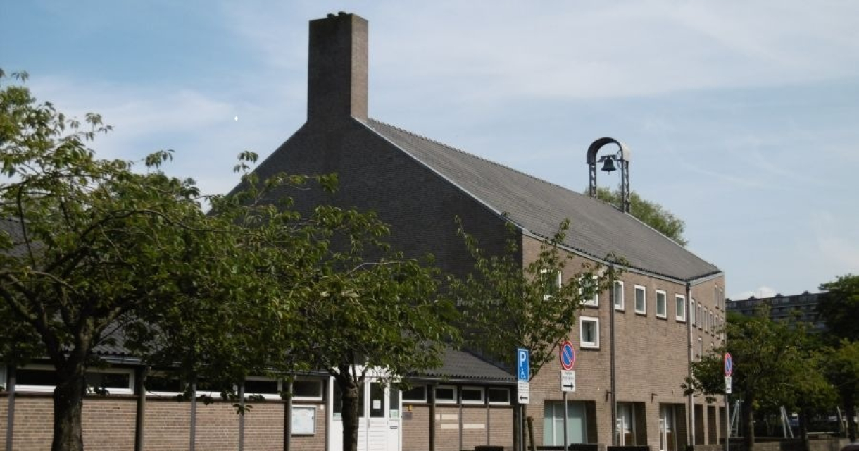 Een stenen gebouw met een klok op het dak en bomen eromheen.
