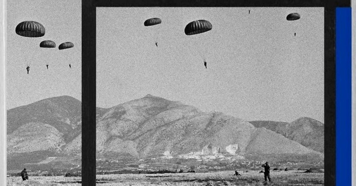 Plusieurs parachutistes descendent dans un champ avec des montagnes en arrière-plan.