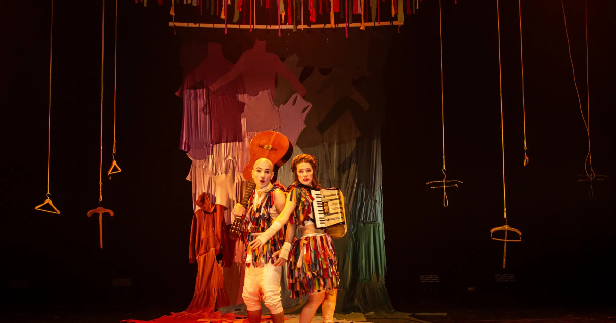 Carnaval van het leven. Twee clowns met instrumenten staan op een kleurrijk podium.