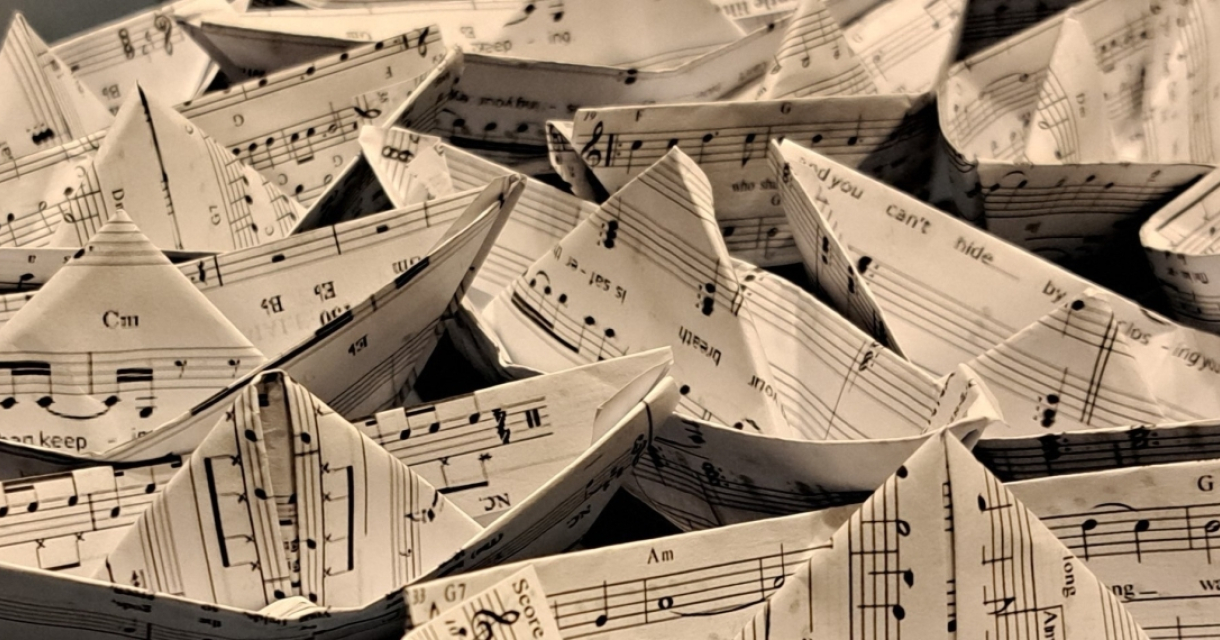 Een verzameling papieren bootjes gemaakt van bladmuziek.