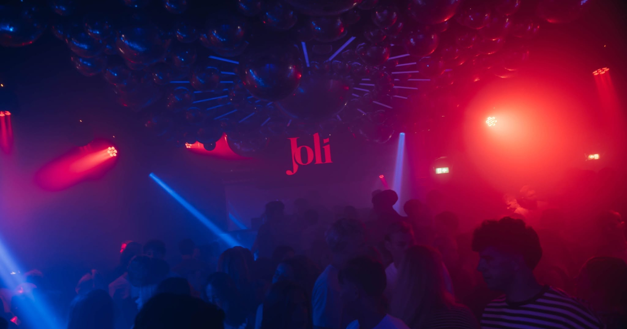 Mensen dansen in een club met kleurrijke lichten. (c) Club Joli