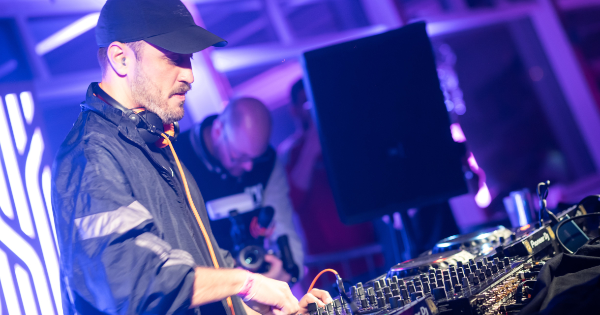 Een DJ draait muziek met een mengpaneel in een clubsetting.