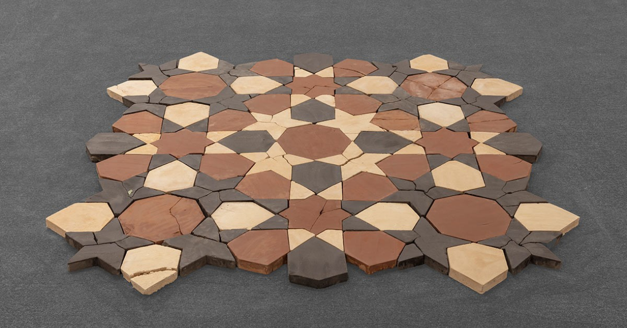 A geometric pattern of ceramic tiles in brown and cream.