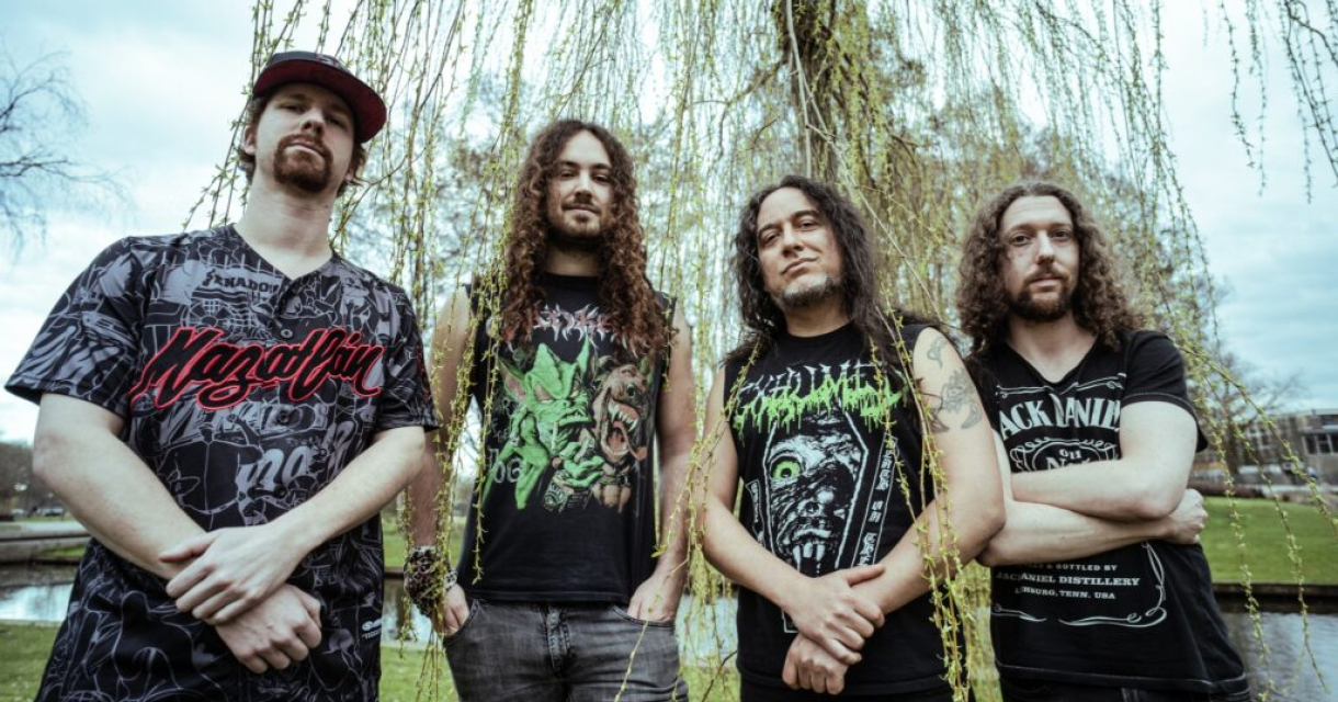 Vier bandleden poseren voor een wilg in het park.