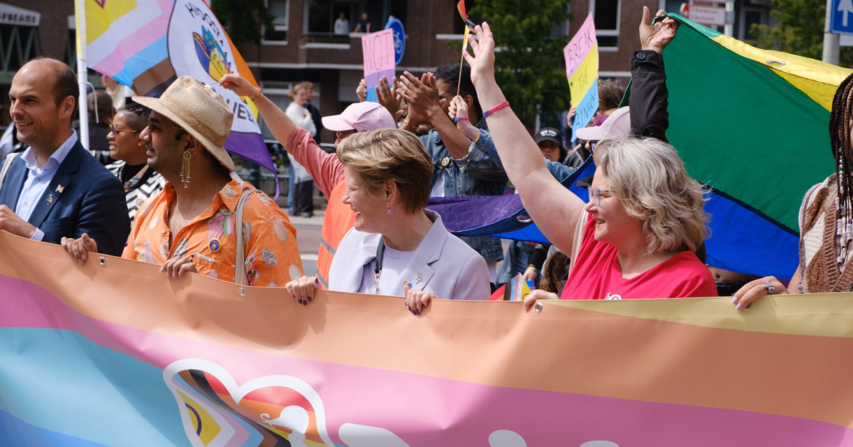 Group of people with a colorful banner during the Pride Parade. (c) COC Haaglanden