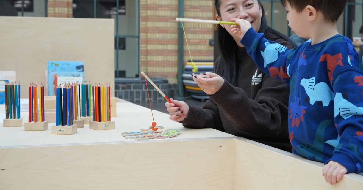 Een vrouw en een kind spelen met kleurrijke speelgoed en tekenmaterialen.