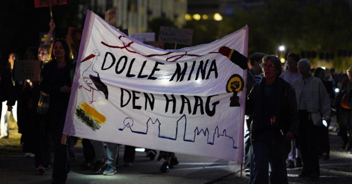 Mensen lopen met een banner 'Dolle Mina Den Haag' tijdens een actie.
