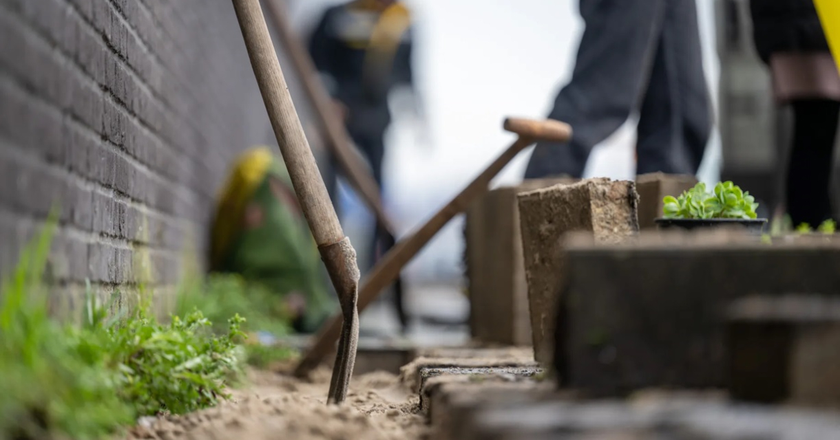 Aanleg van een tuin. Een tuinwerkzaamheden met een schop en mensen op de achtergrond.