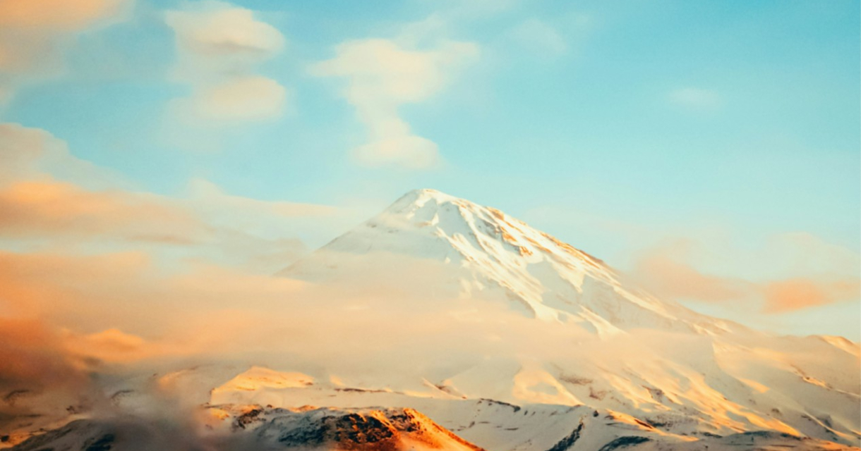 Een majestueuze sneeuwbedekte berg onder een blauwe lucht.
