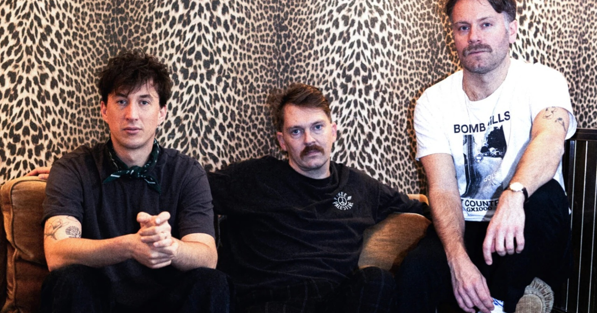 Three men of Ego Dreams sit on a couch against a leopard print wall. Foto: Iris Timmer