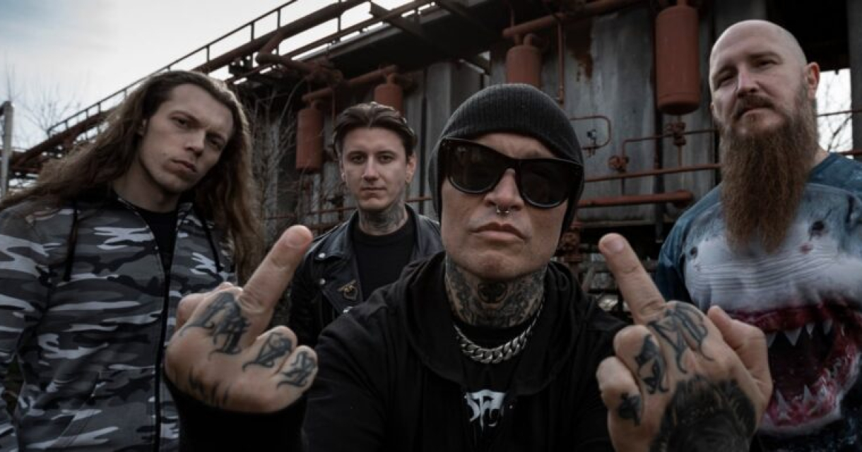 Vier bandleden poseren met een uitdagende houding in een industrieel decor.