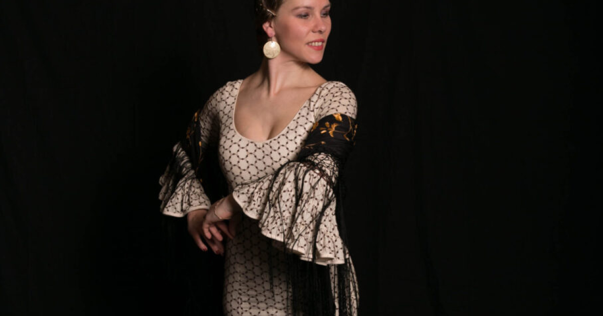 Danseres in traditionele Spaanse kledij. Vrouw in een feestelijke jurk met een zwarte sjawl, lachend.