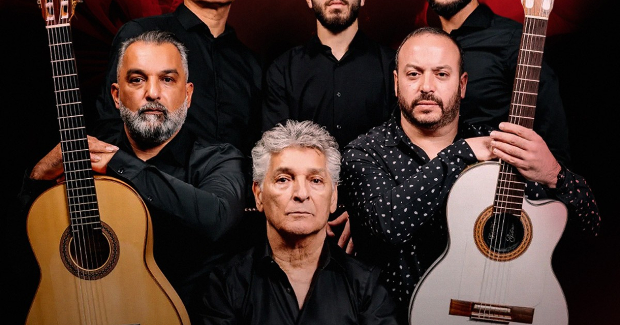 Zes muzikanten in zwarte kleding met gitaren op een rode achtergrond.