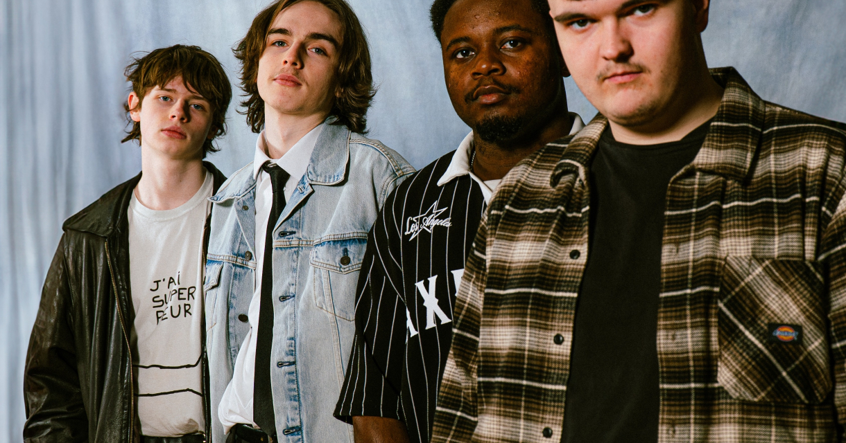 Vier jonge mannen poseren in casual outfits met een neutrale achtergrond.