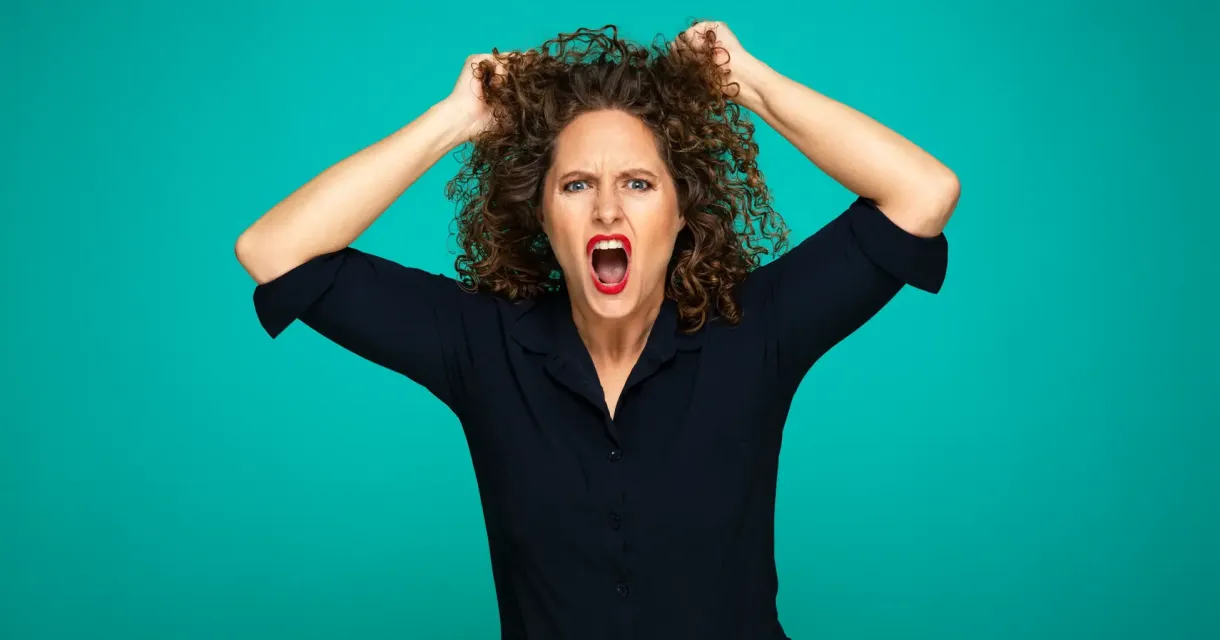 Vrouw met een gefrustreerde uitdrukking trekt aan haar krullende haar