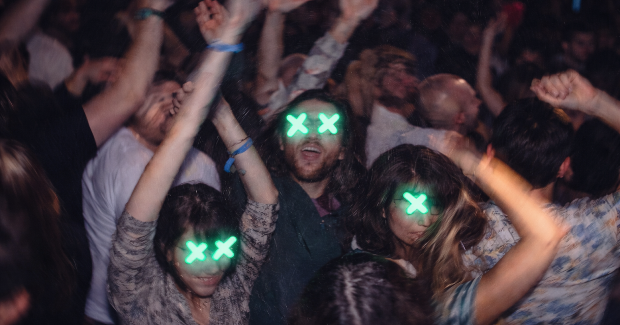 Een drukke club met mensen die dansen en hun handen omhoog steken.