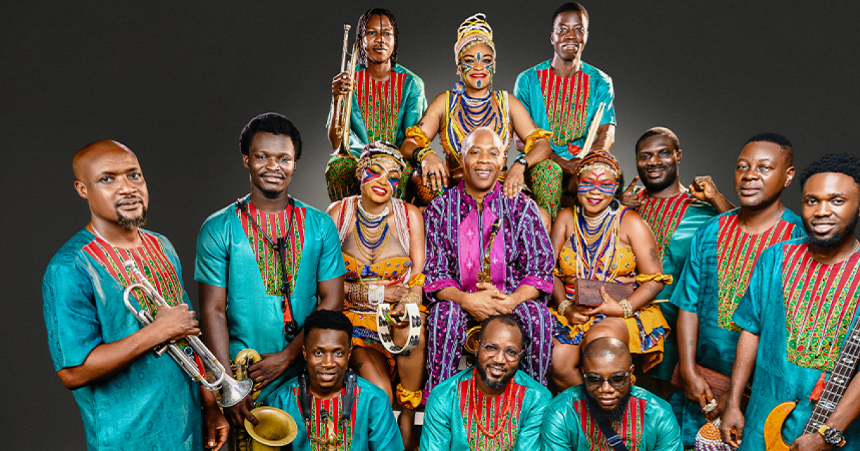 Een groep muzikanten in kleurrijke outfits poseert samen.