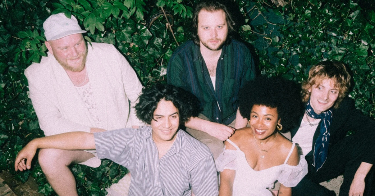 Vijf bandleden van Future Husband poseren samen op een bankje omringd door groen.