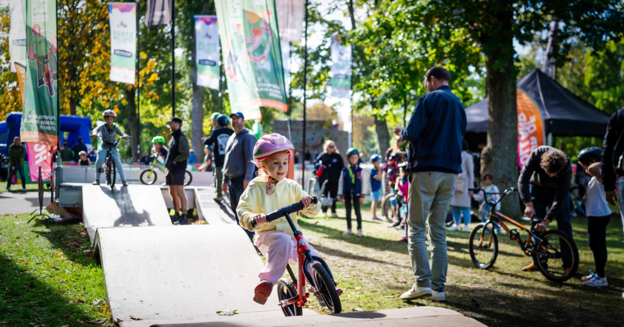 Een meisje rijdt met een fiets op een parcours tussen kijkers.