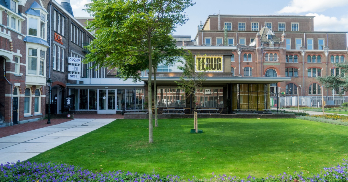 Moderne bouw met een groot gele bord en een groen park.