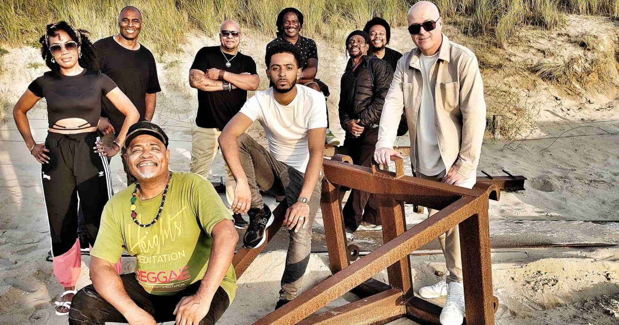 Een enthousiaste groep mensen poseert op het strand.