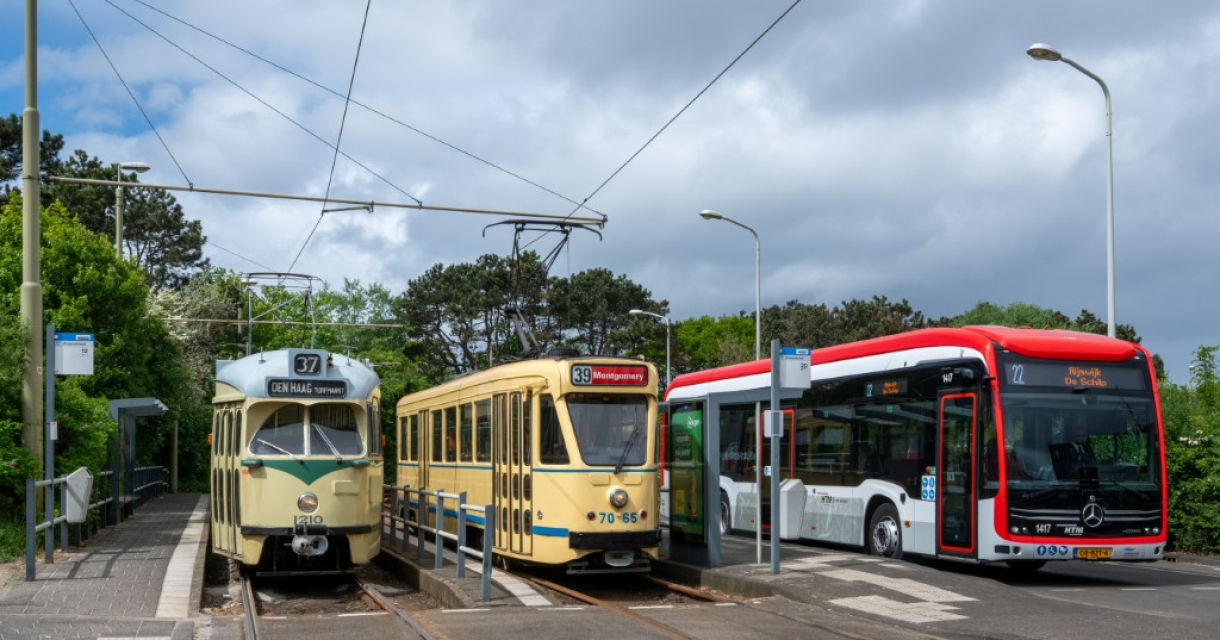 Twee trams en een bus bij een halte in Den Haag.
