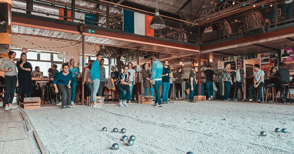 Mensen spelen petanque in een drukke bar.