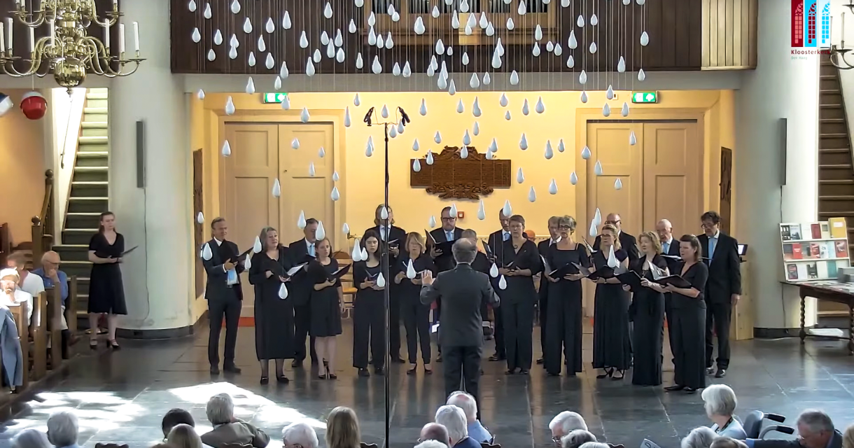 Een koor zingt in een kerk met decoratieve druppels.