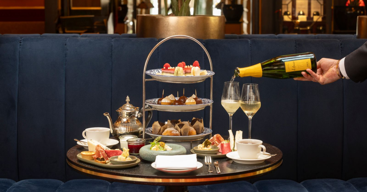 Een elegante tafel met high tea, inclusief thee, gebak en champagne.