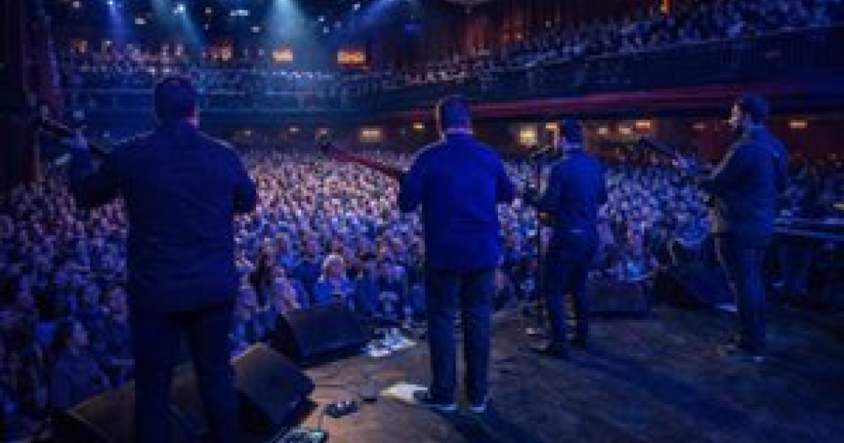 Een band speelt voor een enthousiast publiek in een theater.