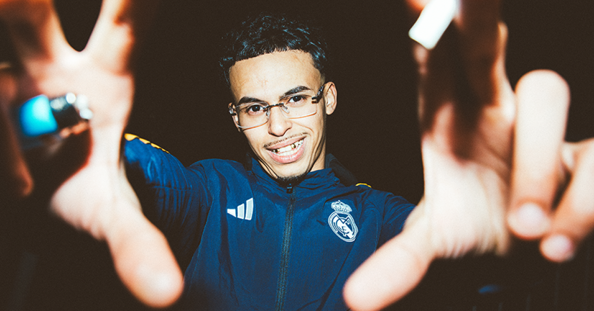 Illie met een ontspannen uitstraling. Illie lacht met een handgebaar voor zijn gezicht.