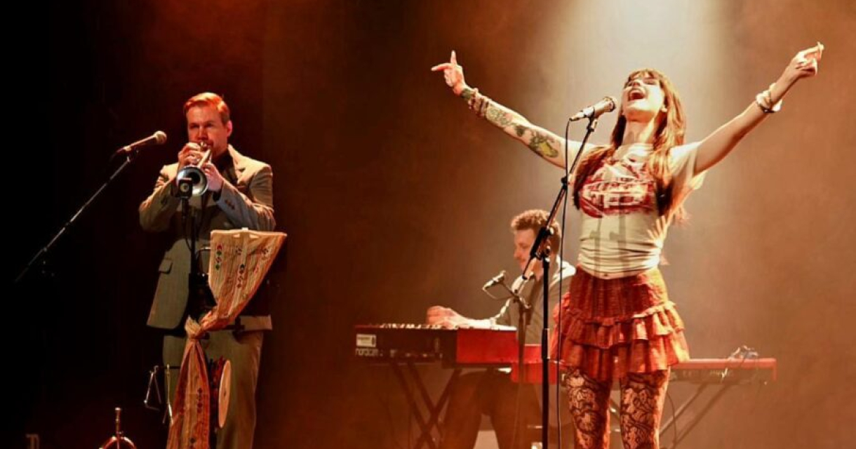 Zangeres performt enthousiast met bandleden op het podium.