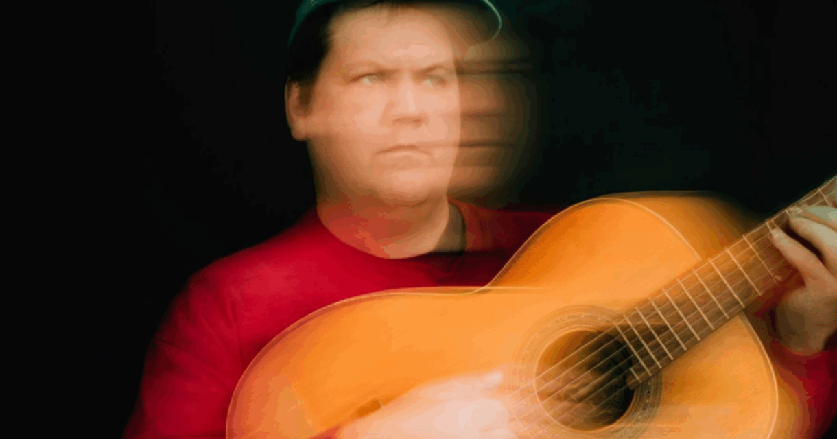 Jake Xerxes Fussell met een gitaar, onscherp door beweging