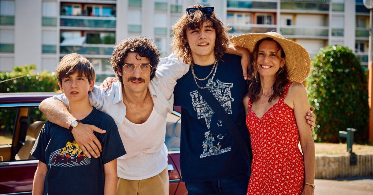 A man, two boys, and a woman pose happily outside.