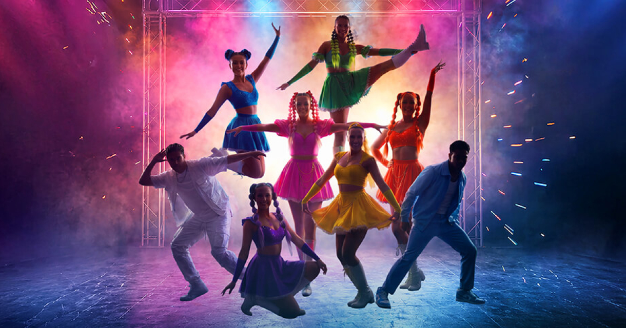 A colorful dance group performs a choreography in bright costumes.