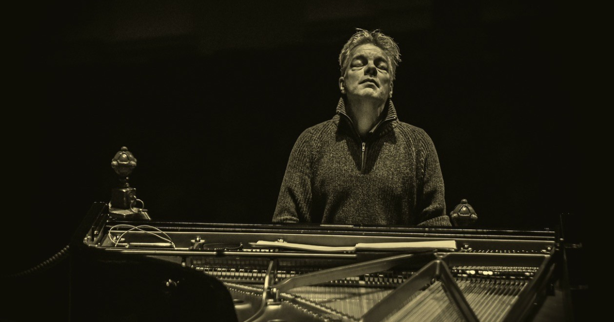 Een pianist kijkt geconcentreerd terwijl hij speelt.