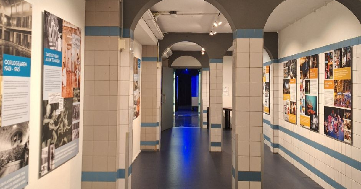 Een gang met exposities aan de muren en blauwe verlichting