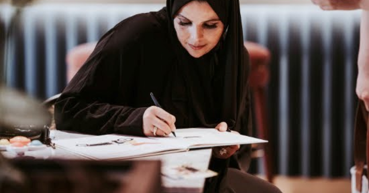 Schrijfster Kamalia Talhaoui schrijvend aan een tafel. 