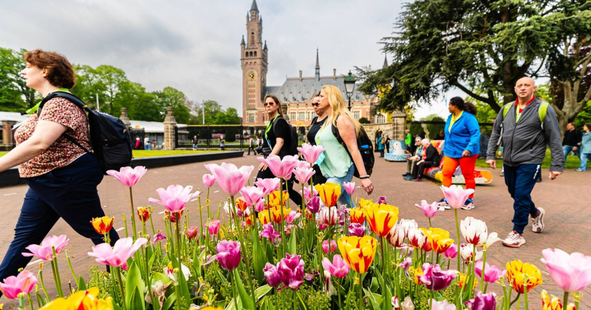 Mensen lopen langs kleurrijke tulpen in Den Haag.
