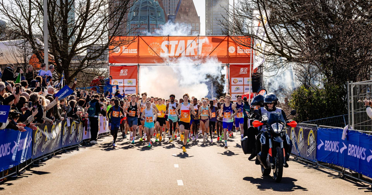 Renners starten een marathon in Den Haag met fans in de achtergrond.