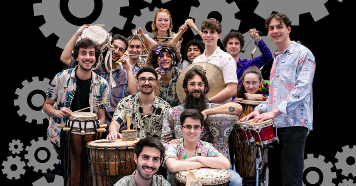 De leden van La Maquina poseren voor de camera in kleurrijke kleding met hun percussie-instrumenten. De groep straalt energie, diversiteit en eenheid uit, klaar voor een ritmisch avontuur.