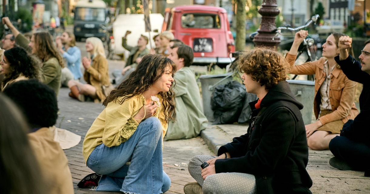 Mensen zitten op de grond en participeren in een bijeenkomst.