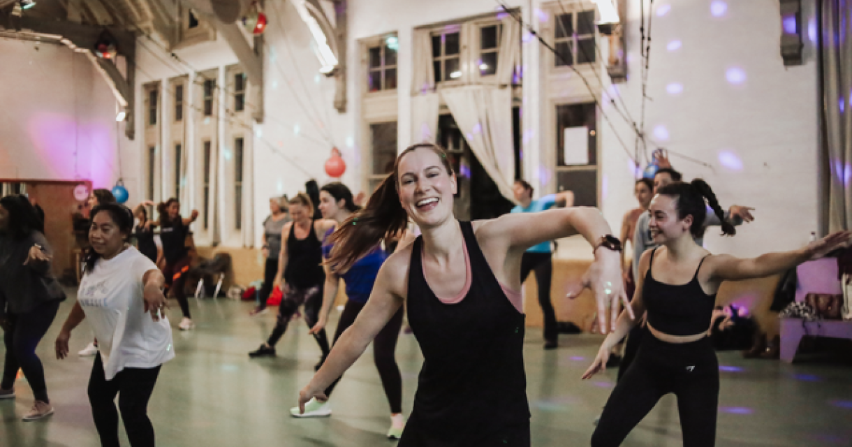 Een groep vrouwen danst samen in een studio met vrolijke ambiance.