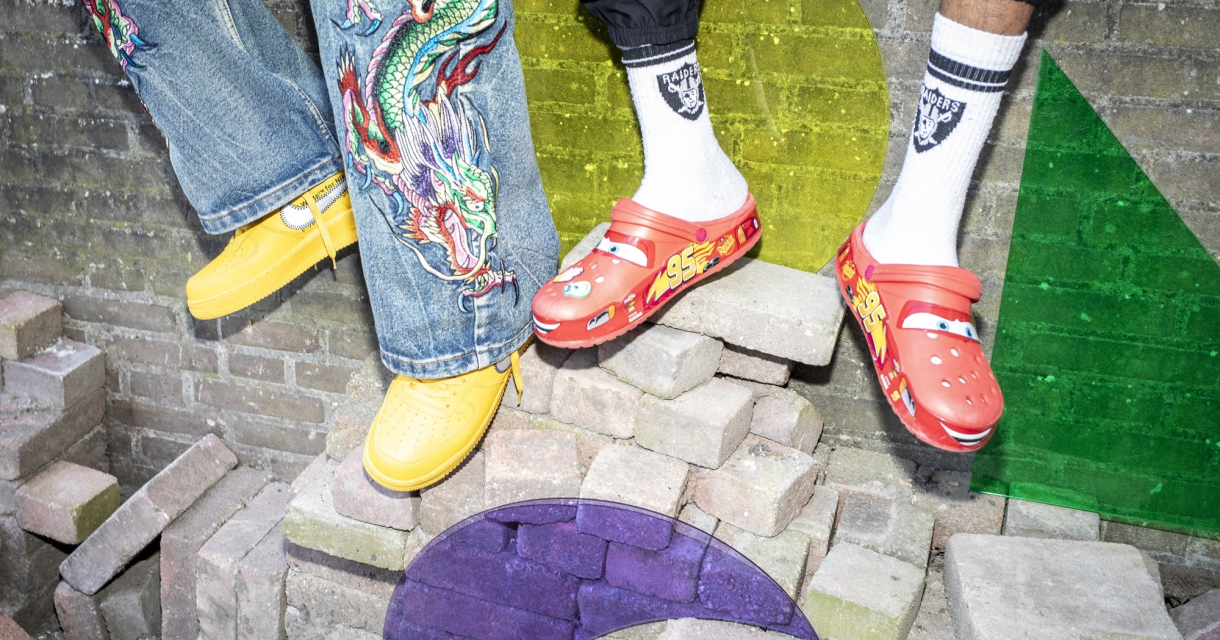 Twee paar kleurrijke schoenen staan op stenen met een muur op de achtergrond.