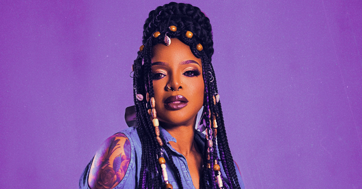 Portret van zangeres Leela James voor paarse achtergrond.