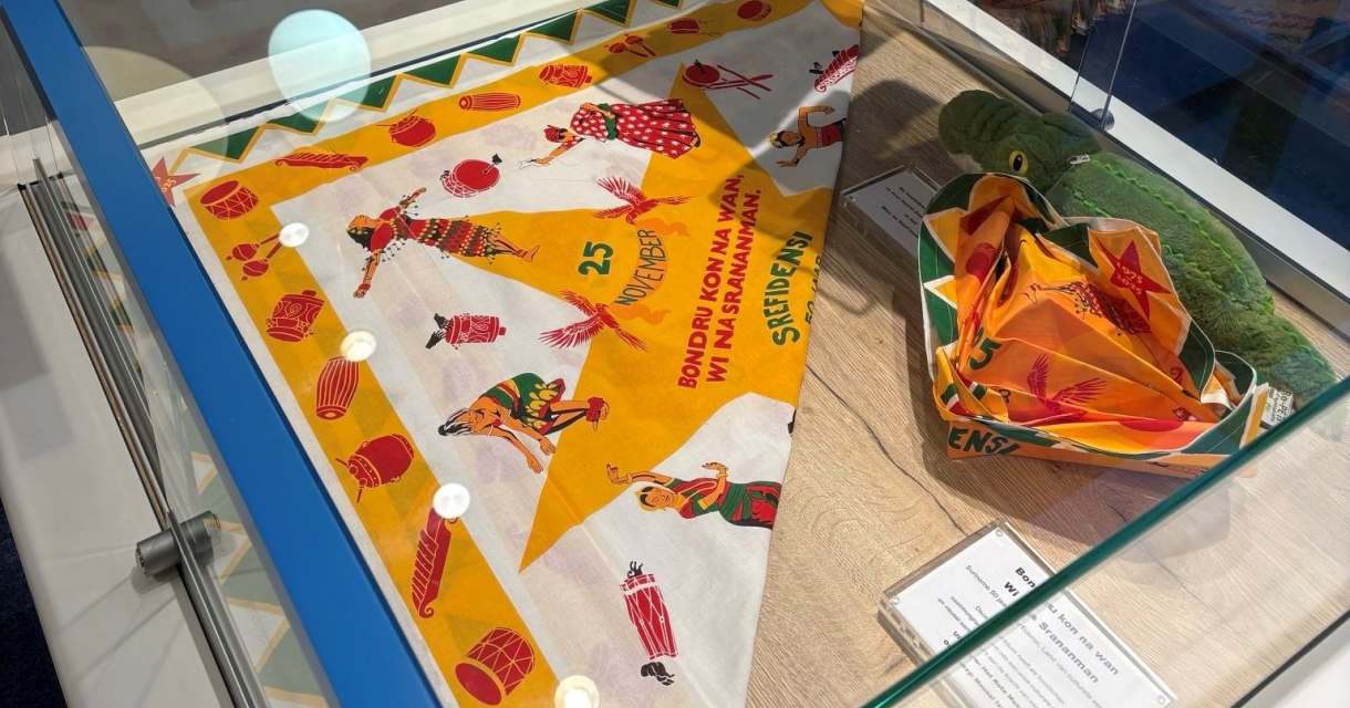 Een etalage met kleurrijke souvenirs, waaronder boeken, een sjaal met afbeeldingen van dansers en een knuffel.