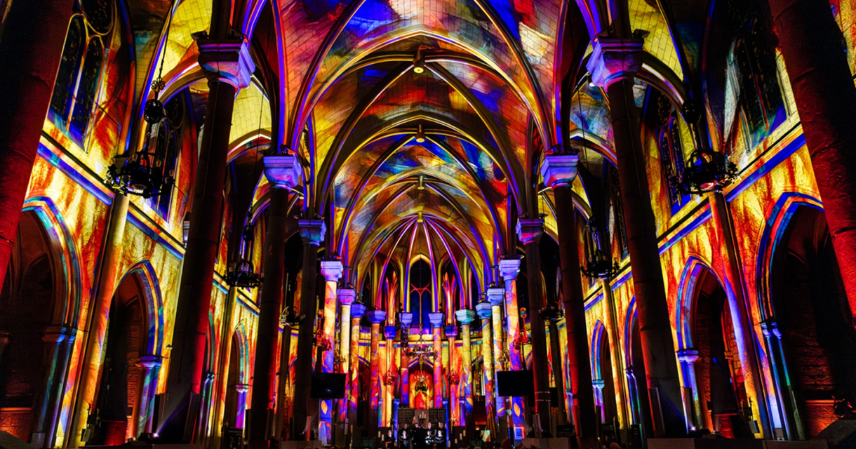 Een kerk met kleurrijke lichtprojecties op de muren en het plafond. 