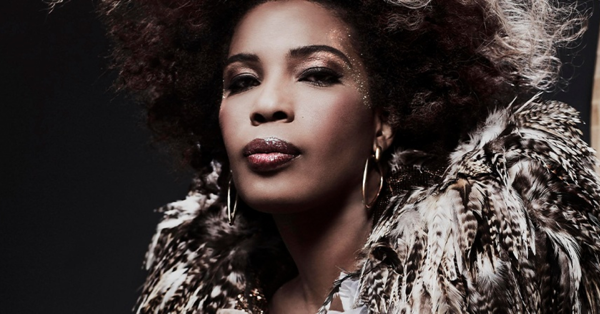 Macy Gray. Een vrouw met krullend haar en een opvallende outfit.